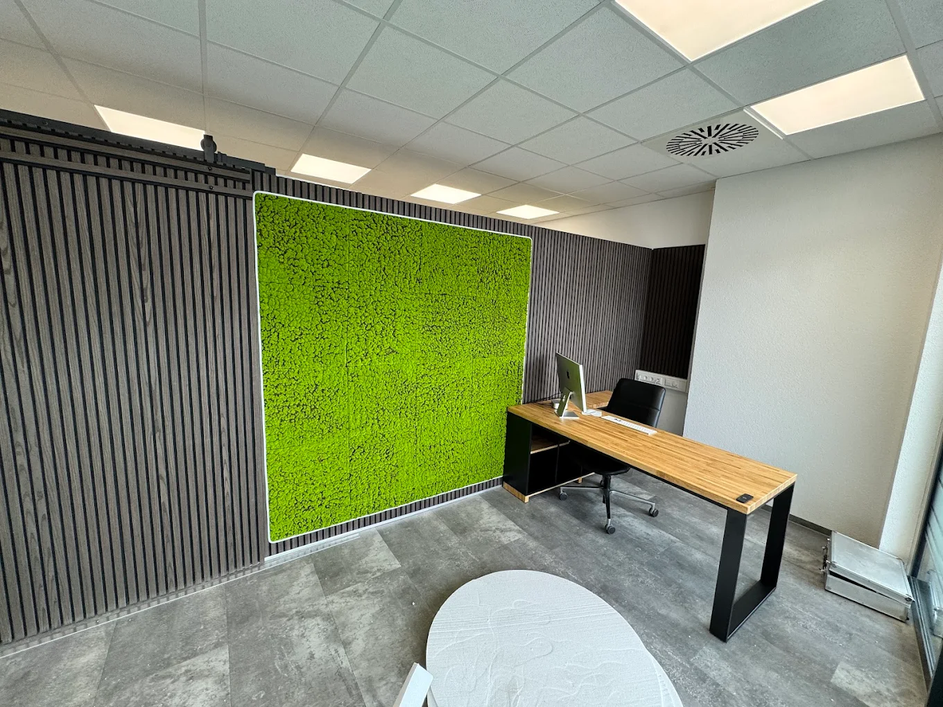 Un bureau d'angle adossé à un mur végétalisé de mousse pour l'auto-école ZERO de Friedrichshafen (Allemagne)